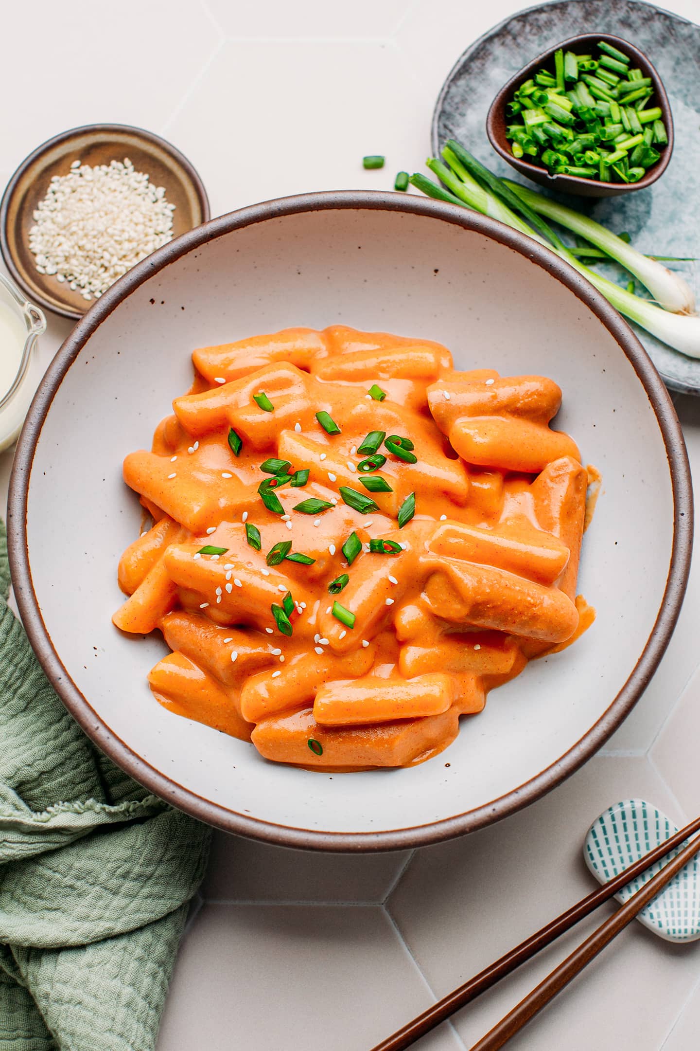 Rosé tteokbokki topped with scallions in a bowl.