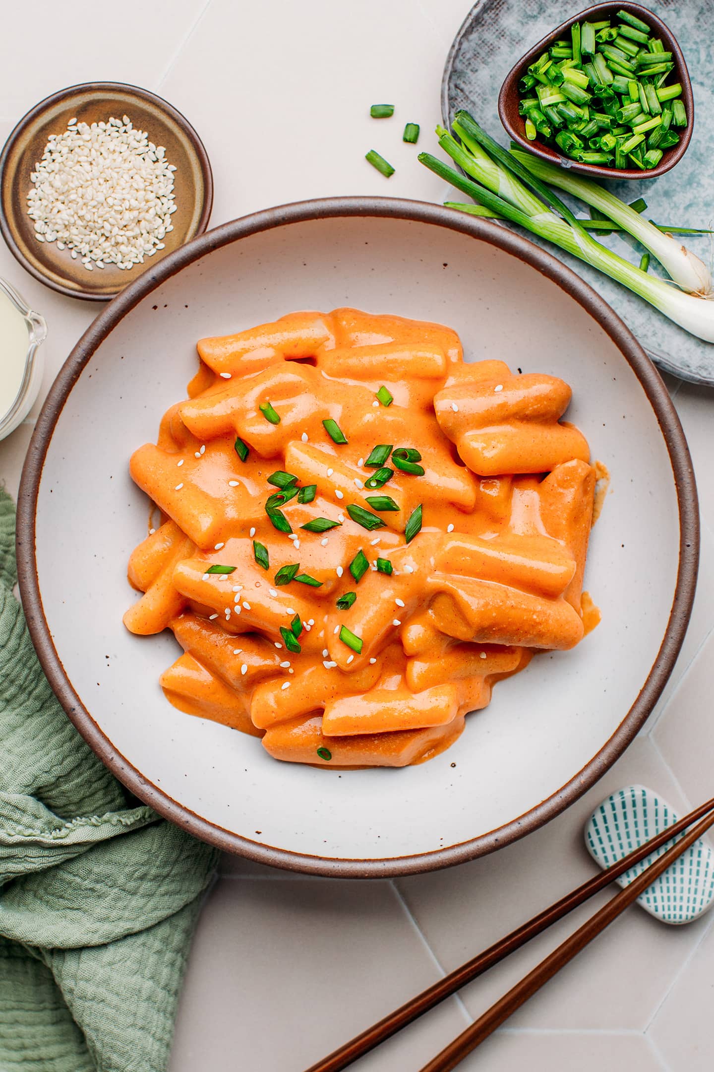 Rosé tteokbokki topped with scallions in a bowl.