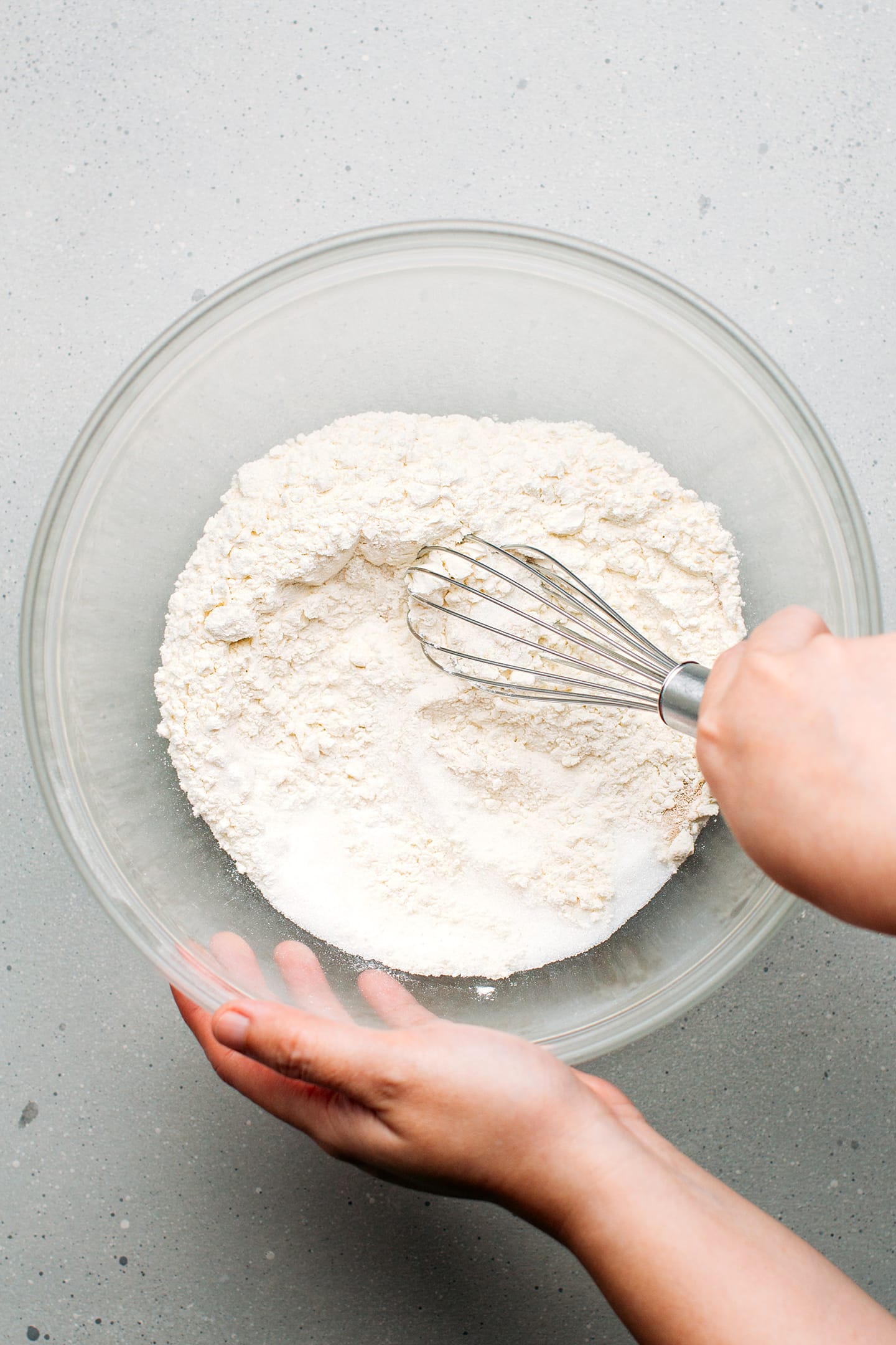 Whisking flour, sugar, and yeast in a mixing bowl.