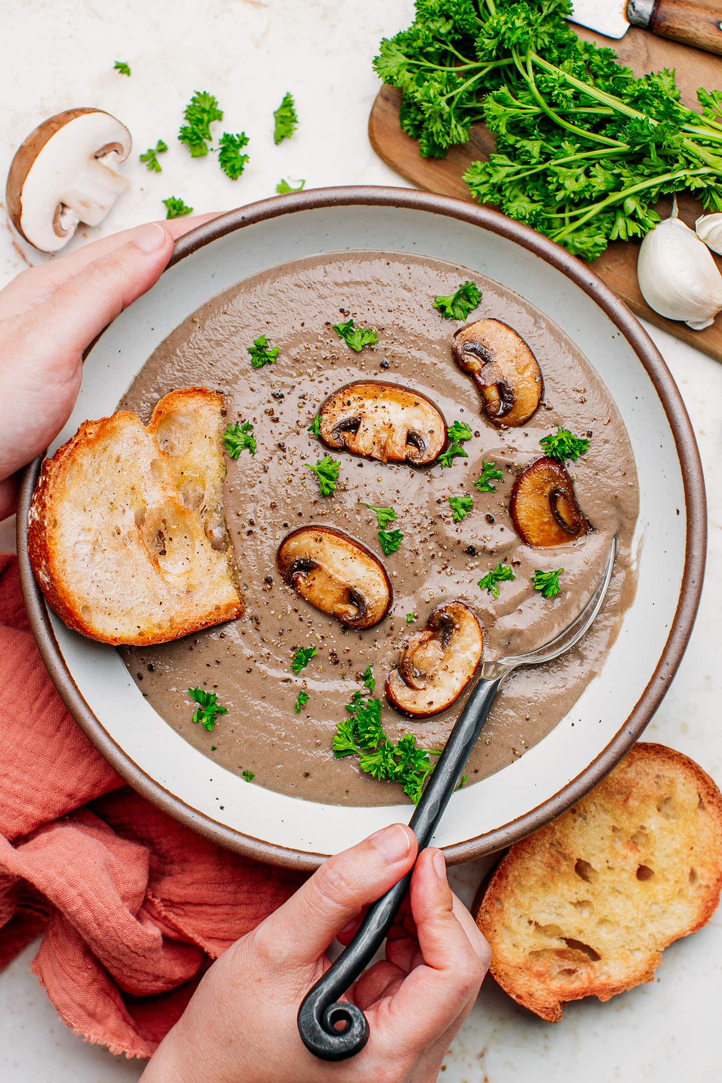Holding a bowl of mushroom soup with bread slices.