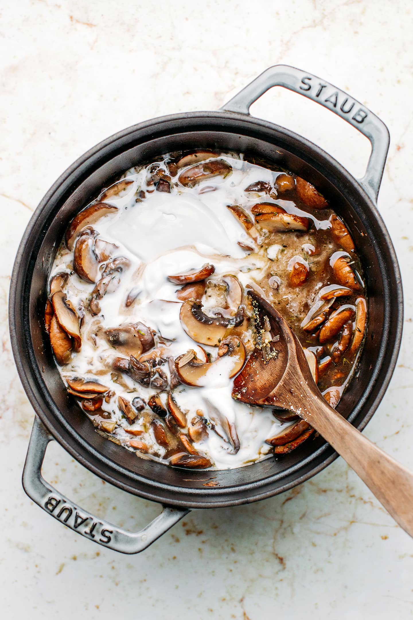 Sautéed mushrooms and coconut milk in a pot.