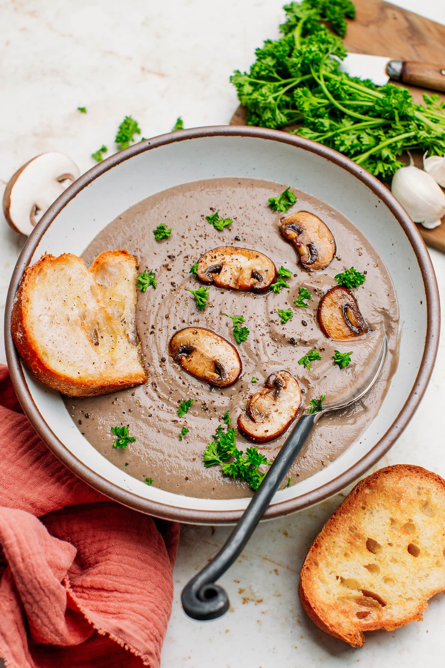 Mushroom soup topped with parsley and served with toasted bread.