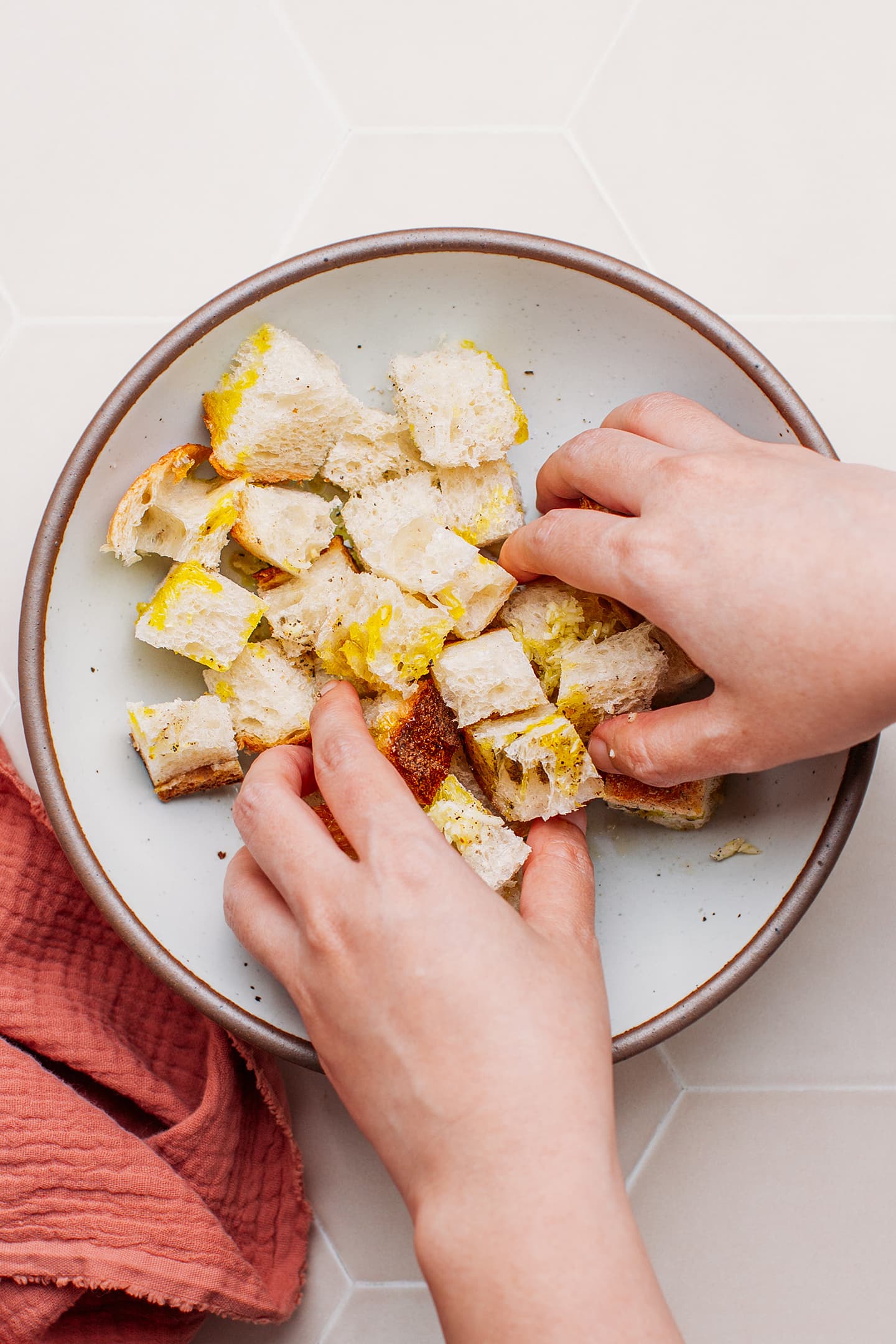 Tossing diced bread with olive oil.