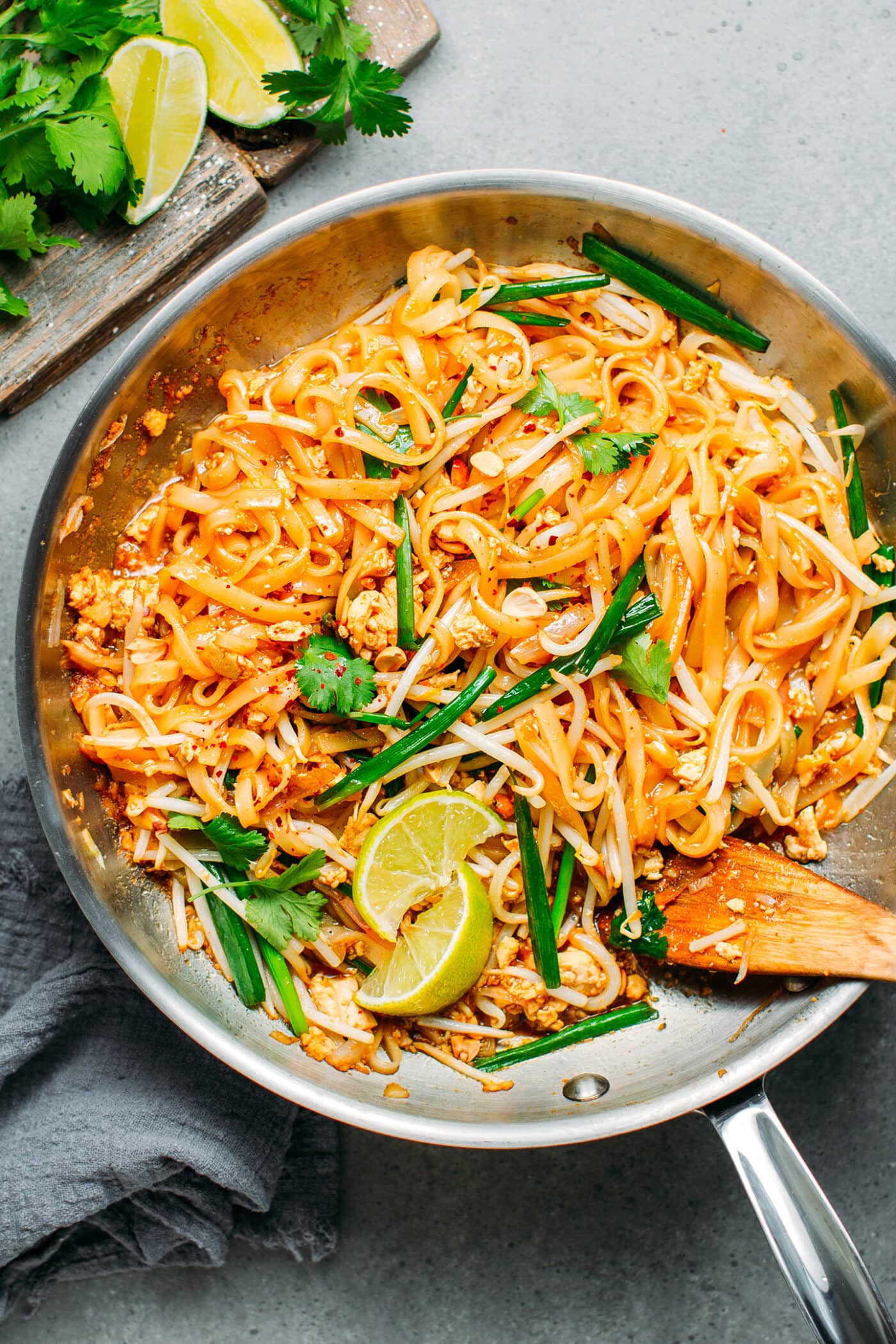 Vegan Pad Thai in a skillet with lime wedges.