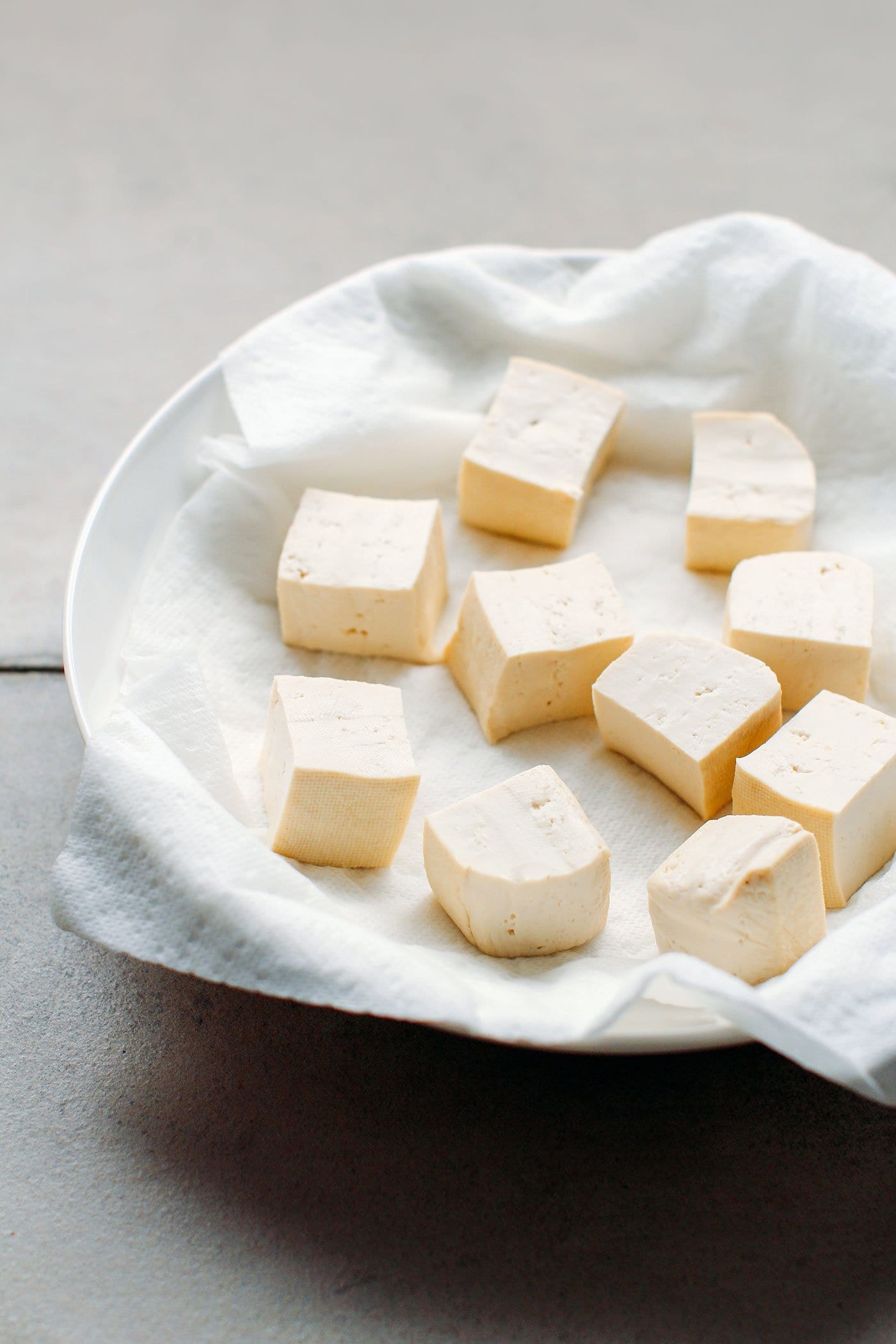 Tofu cubes on a plate with kitchen paper towel.