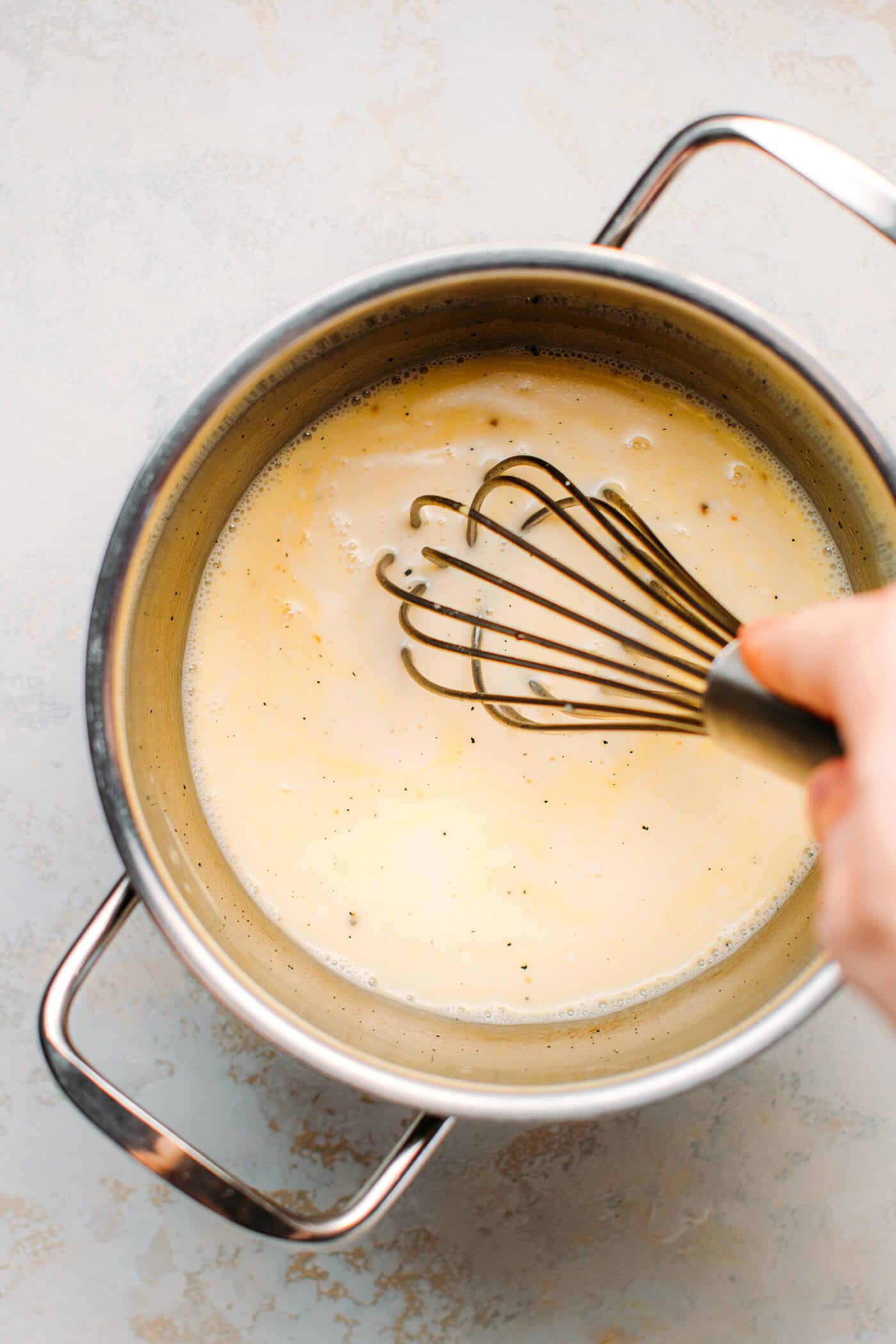 Whisking vanilla custard in a saucepan.