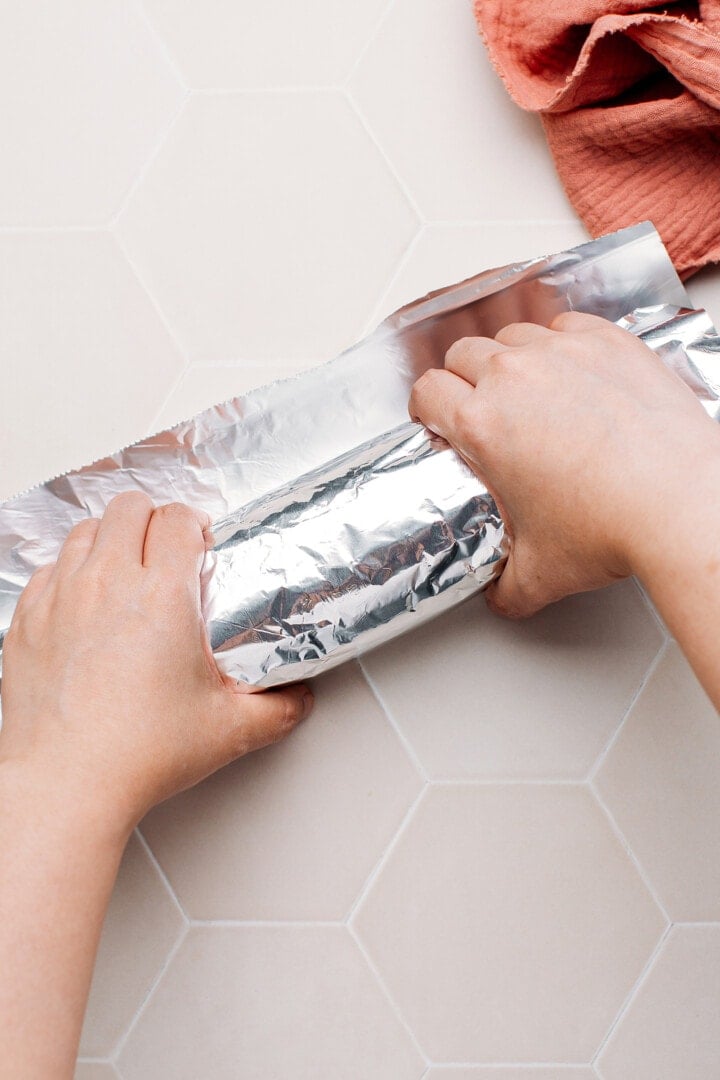 Wrapping a loaf of seitan in aluminum foil.