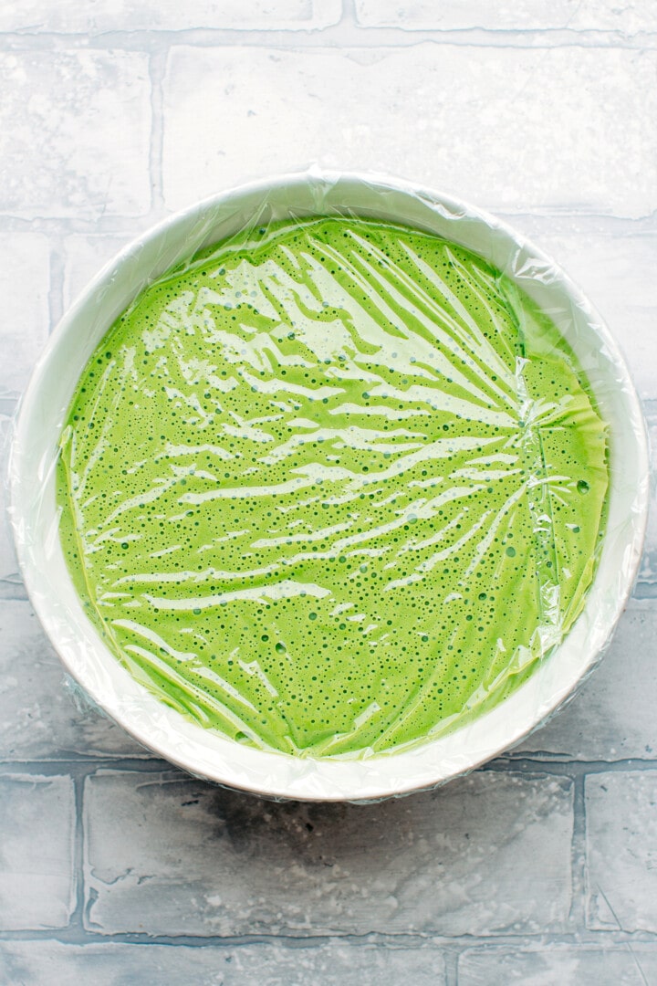 Matcha ice cream base in a bowl covered with plastic wrap.