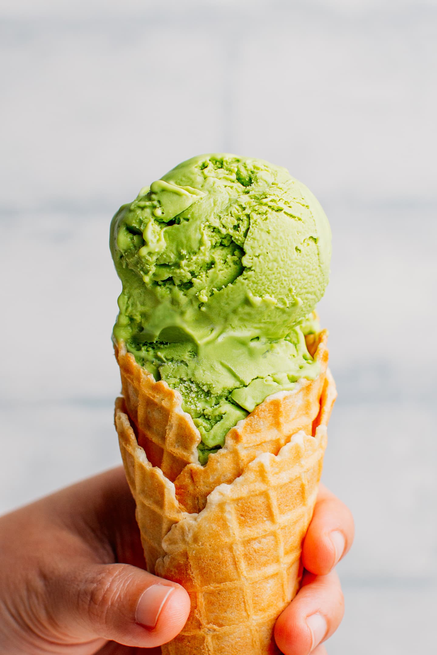 Two scoops of matcha ice cream in a waffle cone.