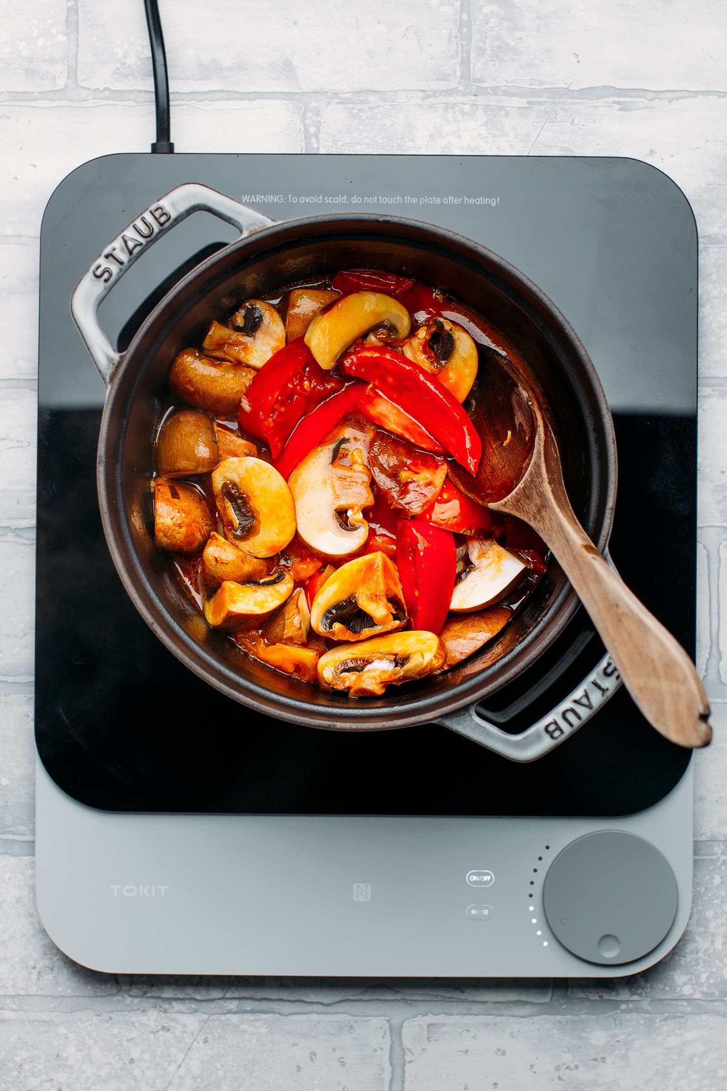 Sautéed mushrooms and tomatoes in a pot.