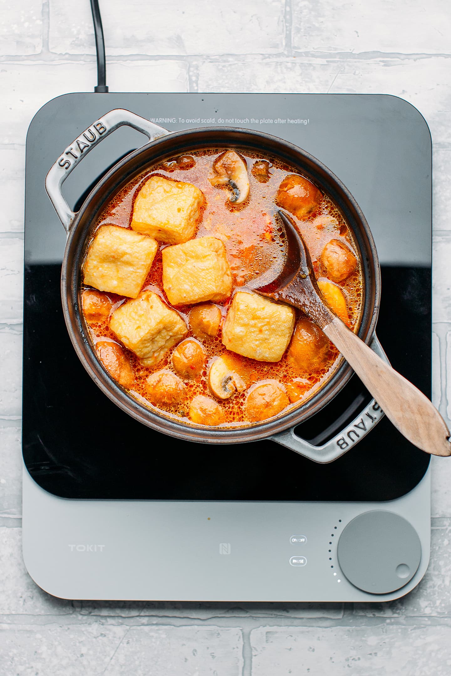 Tomato broth with fried tofu in a pot.