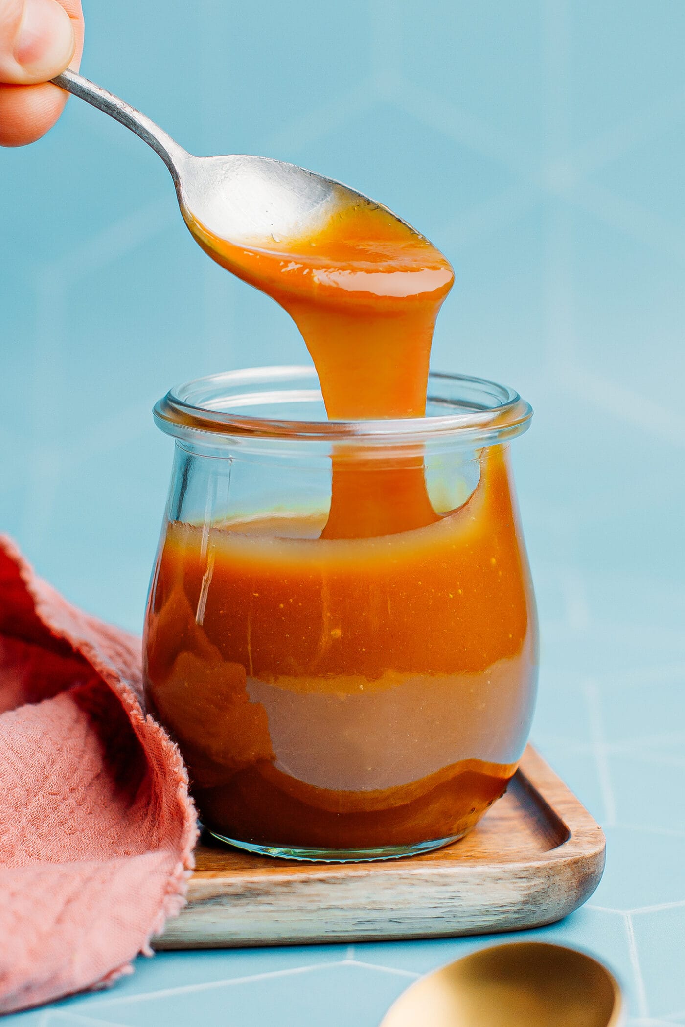 Dipping a spoon in vegan salted caramel sauce.