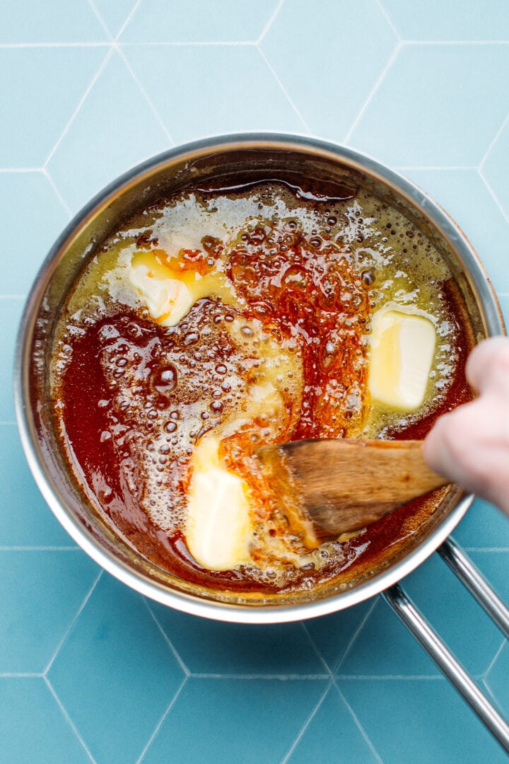 Adding butter to caramel in a saucepan.
