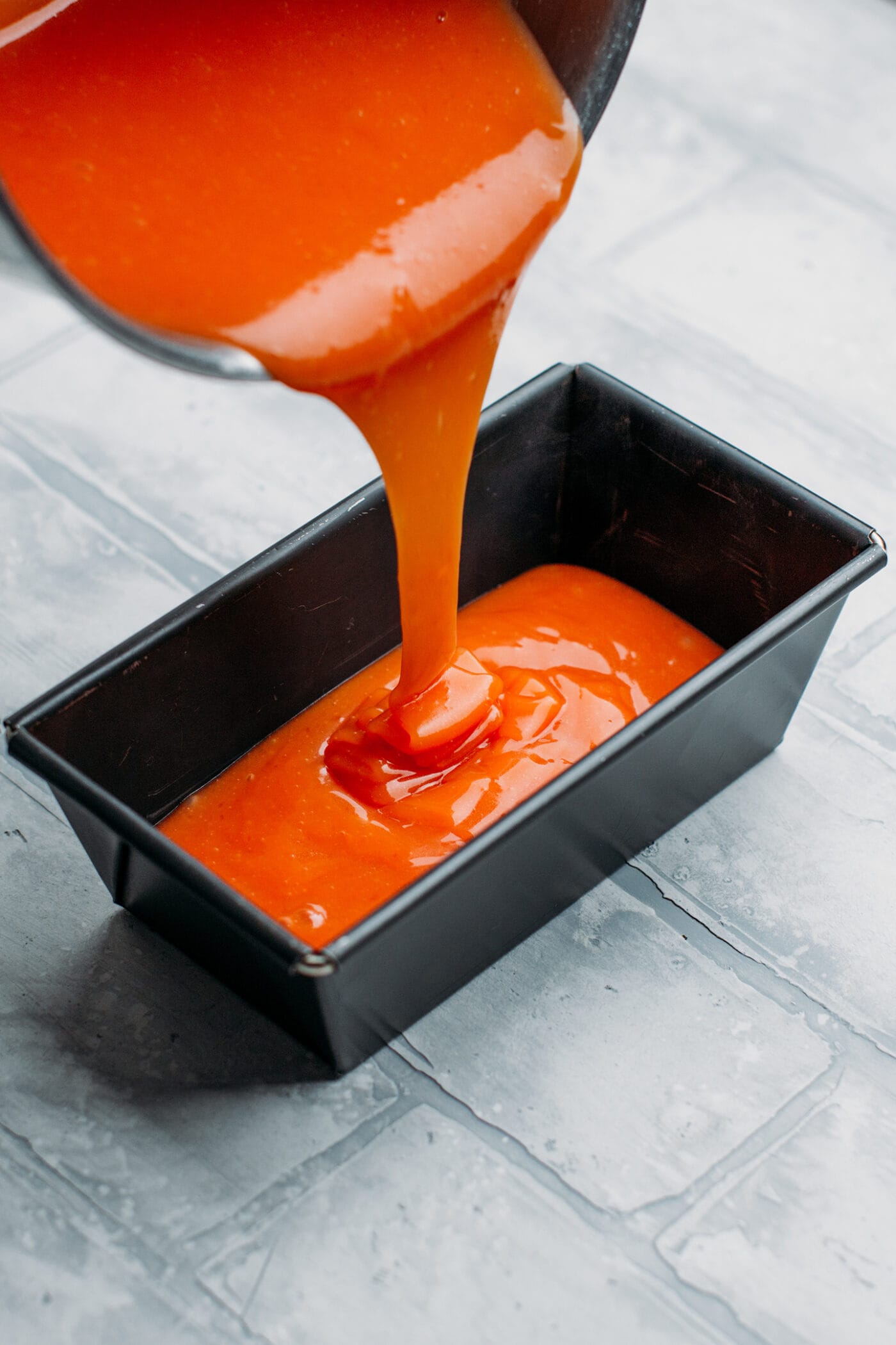 Pouring orange jelly into a pan.