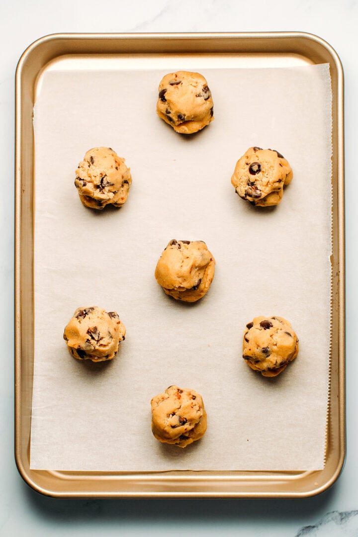 Raw cookie dough balls on a baking sheet.