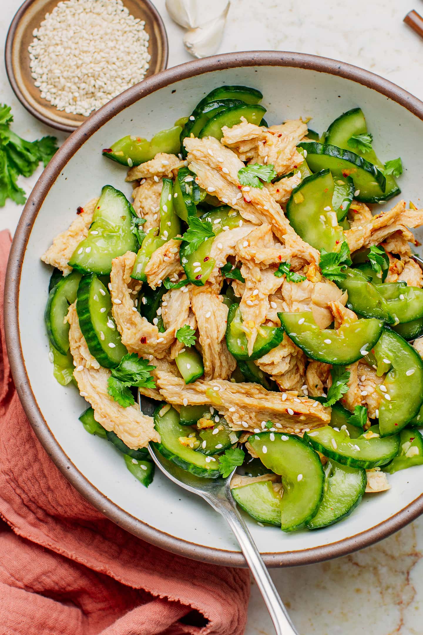 Vegan chicken cucumber salad topped with toasted sesame seeds and fresh herbs.