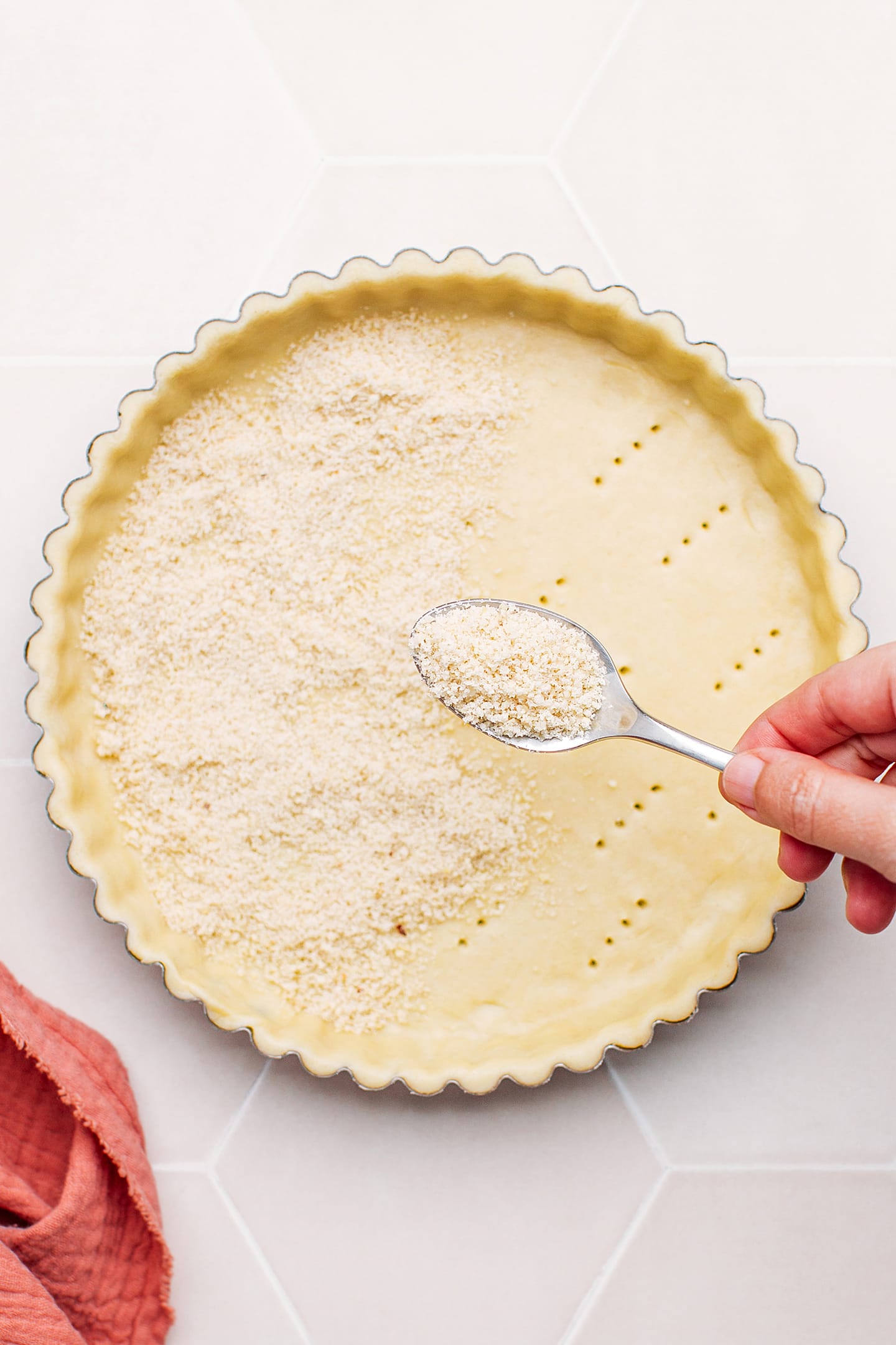 Sprinkling almond flour on an unbaked pie crust.