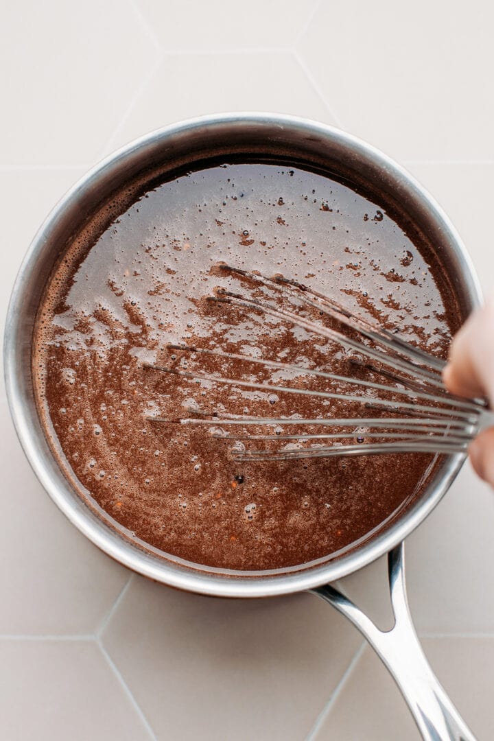 Whisking melted chocolate with milk in a pan.
