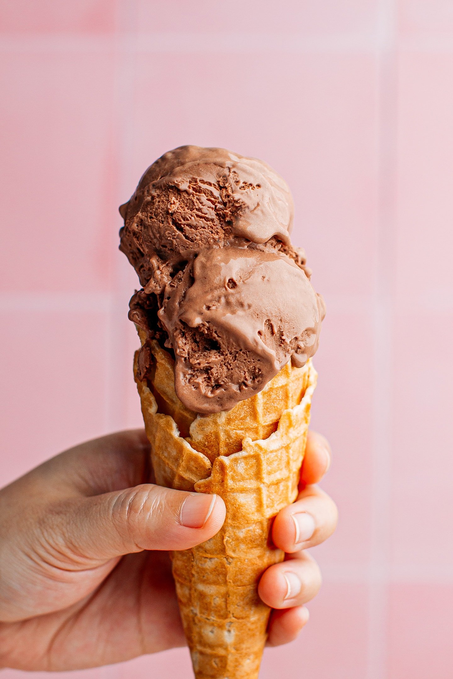 Two scoops of chocolate ice cream in a waffle cone.