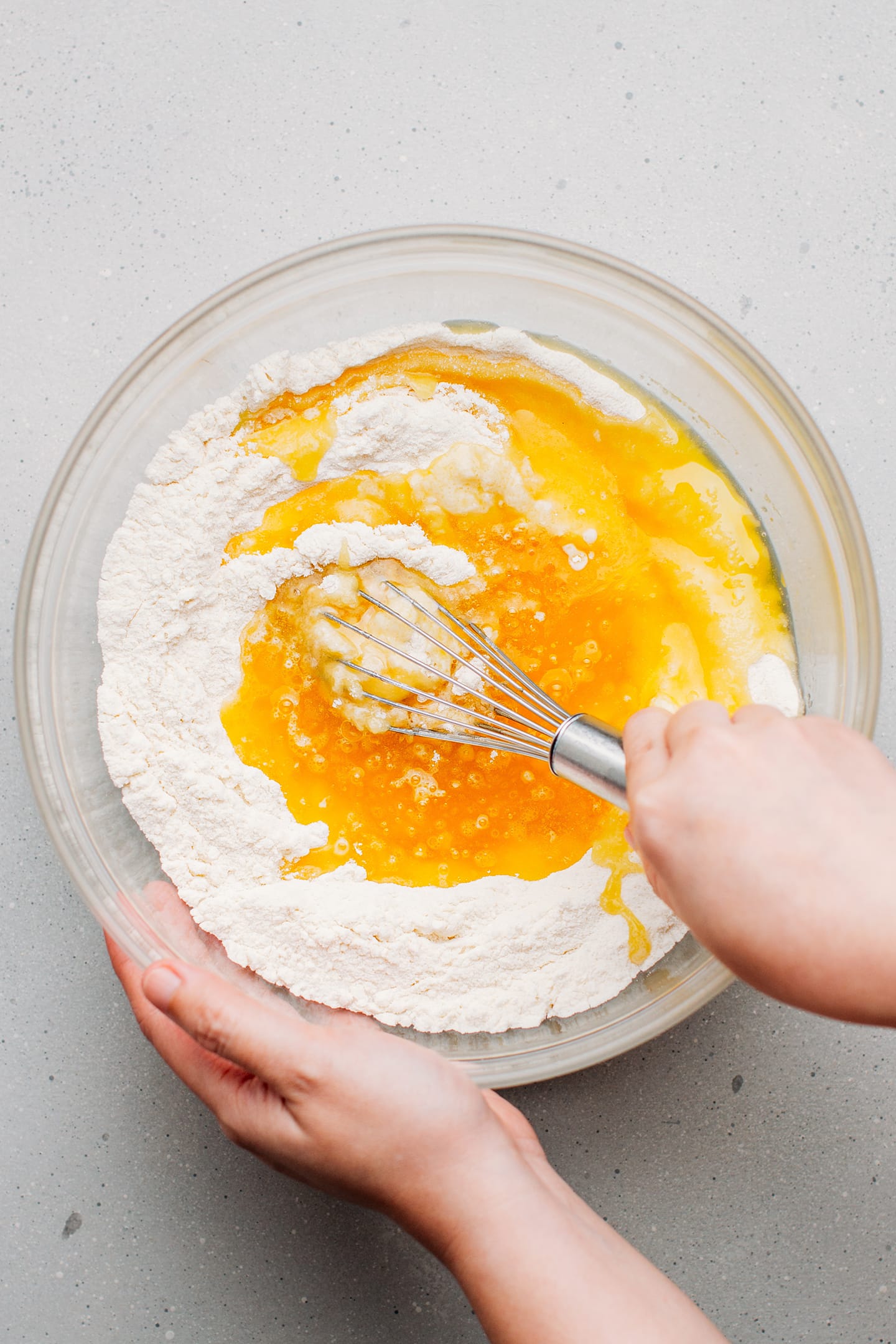 Whisking melted butter with flour and yogurt in a mixing bowl.