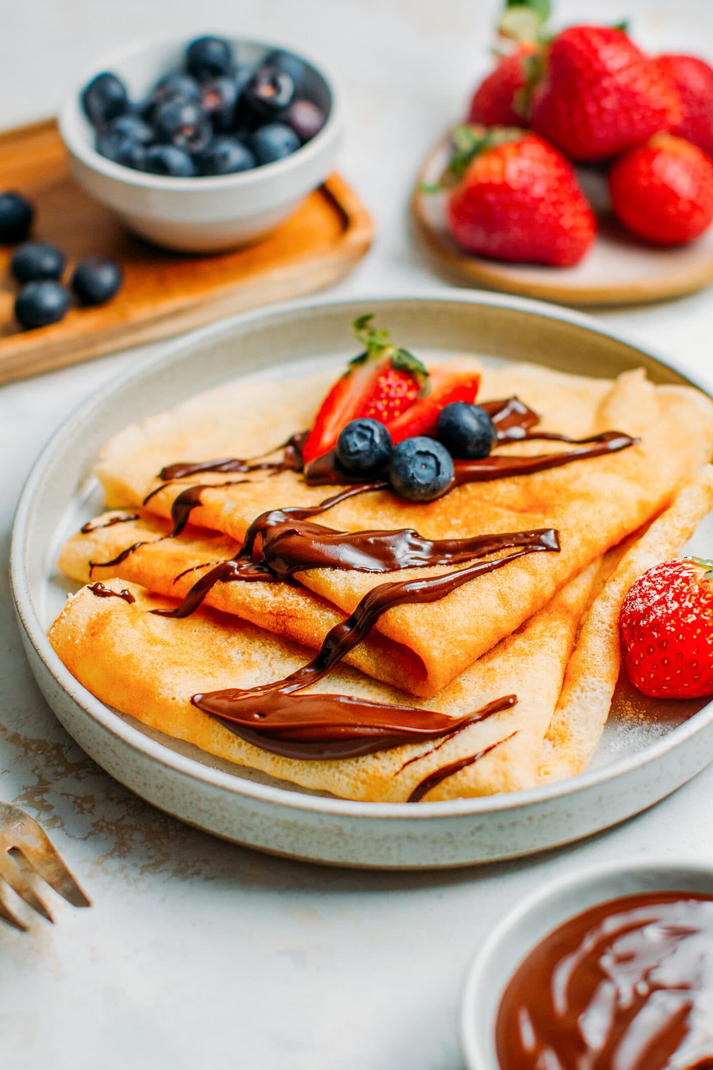 Folded crêpes topped with melted chocolate and berries.