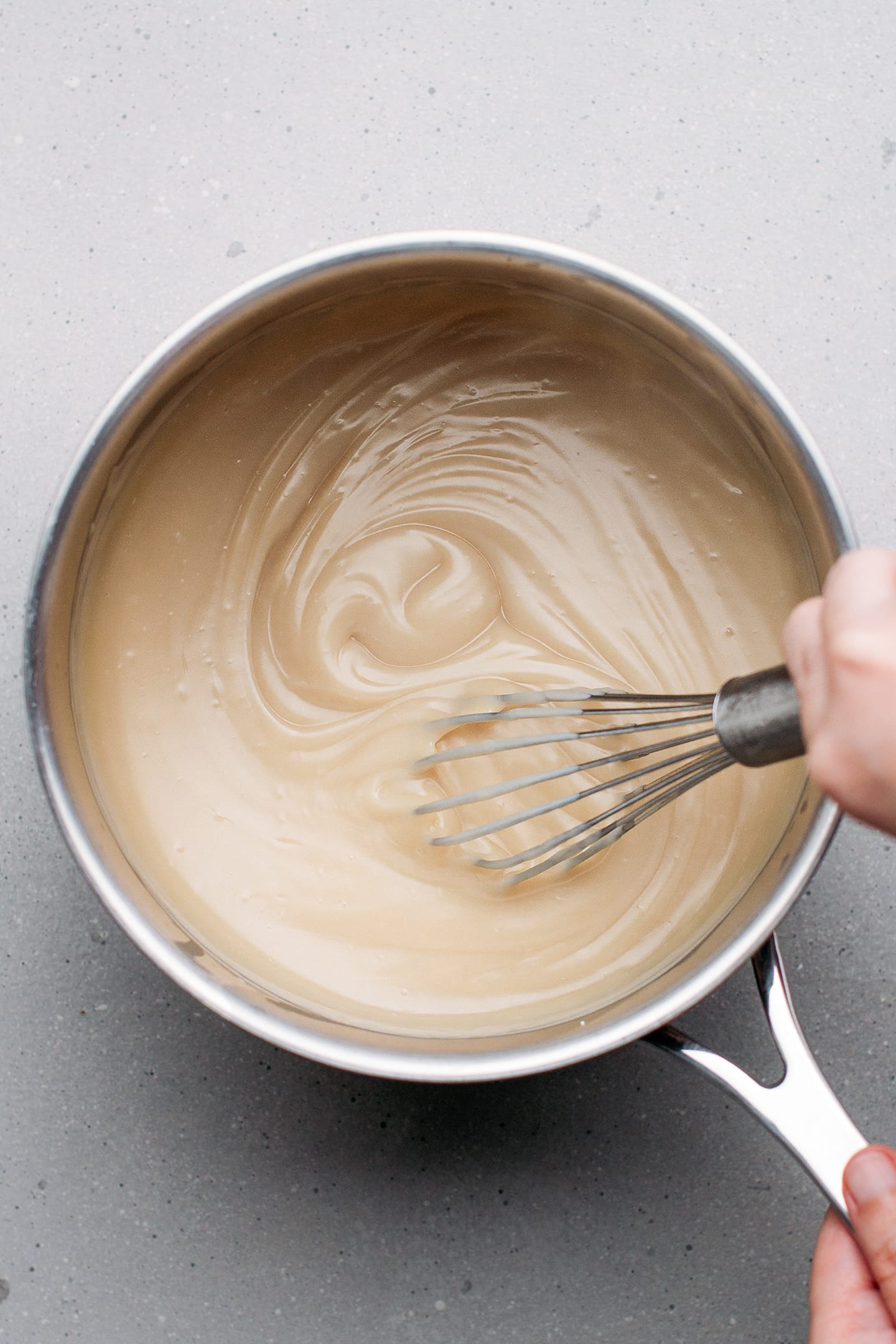 Whisking almond milk cream in a saucepan.