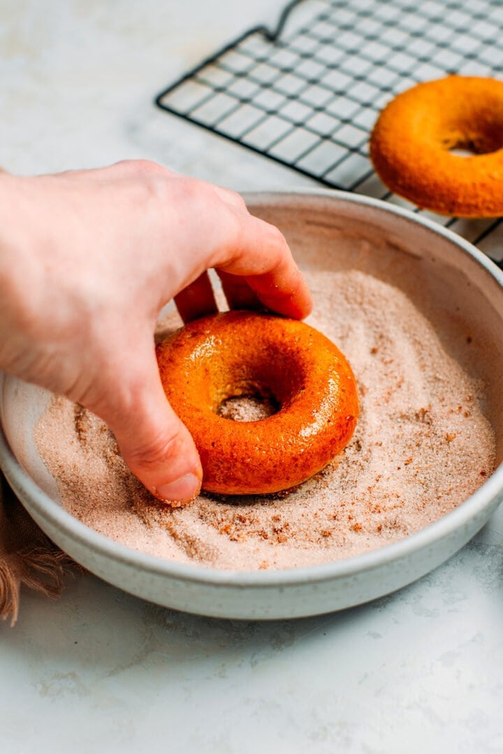 Dipping vegan donuts in cinnamon sugar