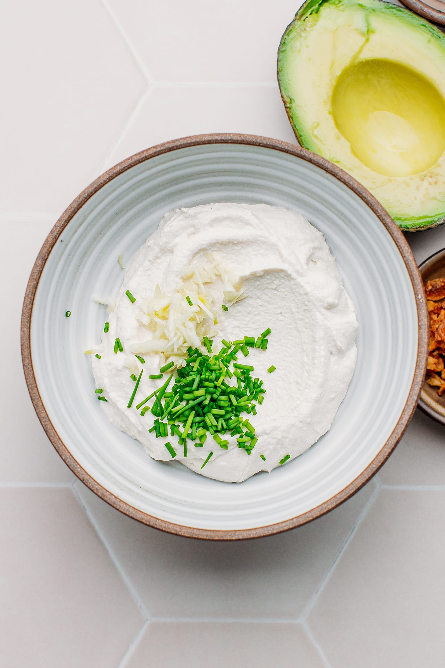 Cream cheese, garlic, and chives in a bowl.