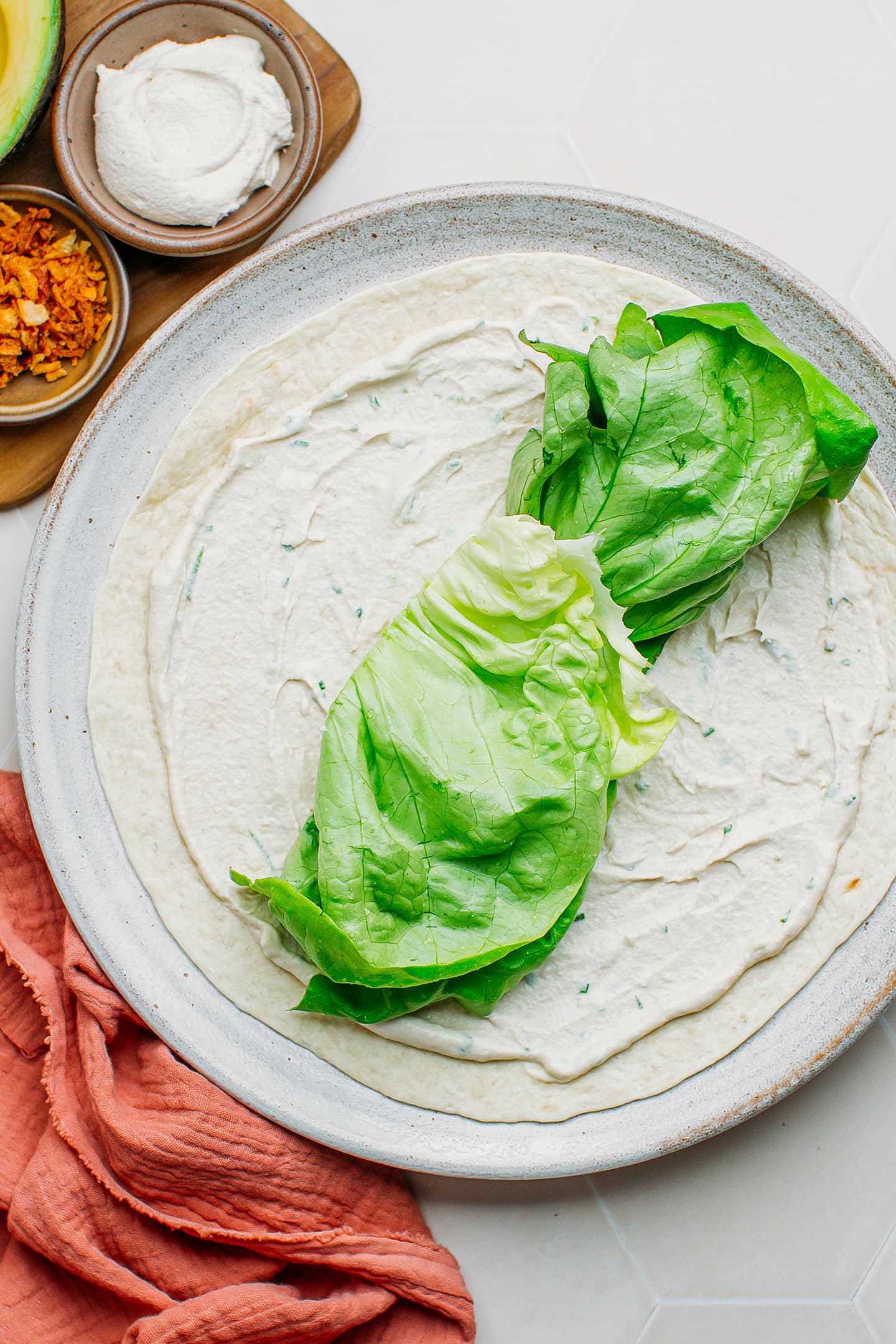 Lettuce and cream cheese on top of a tortilla wrap.