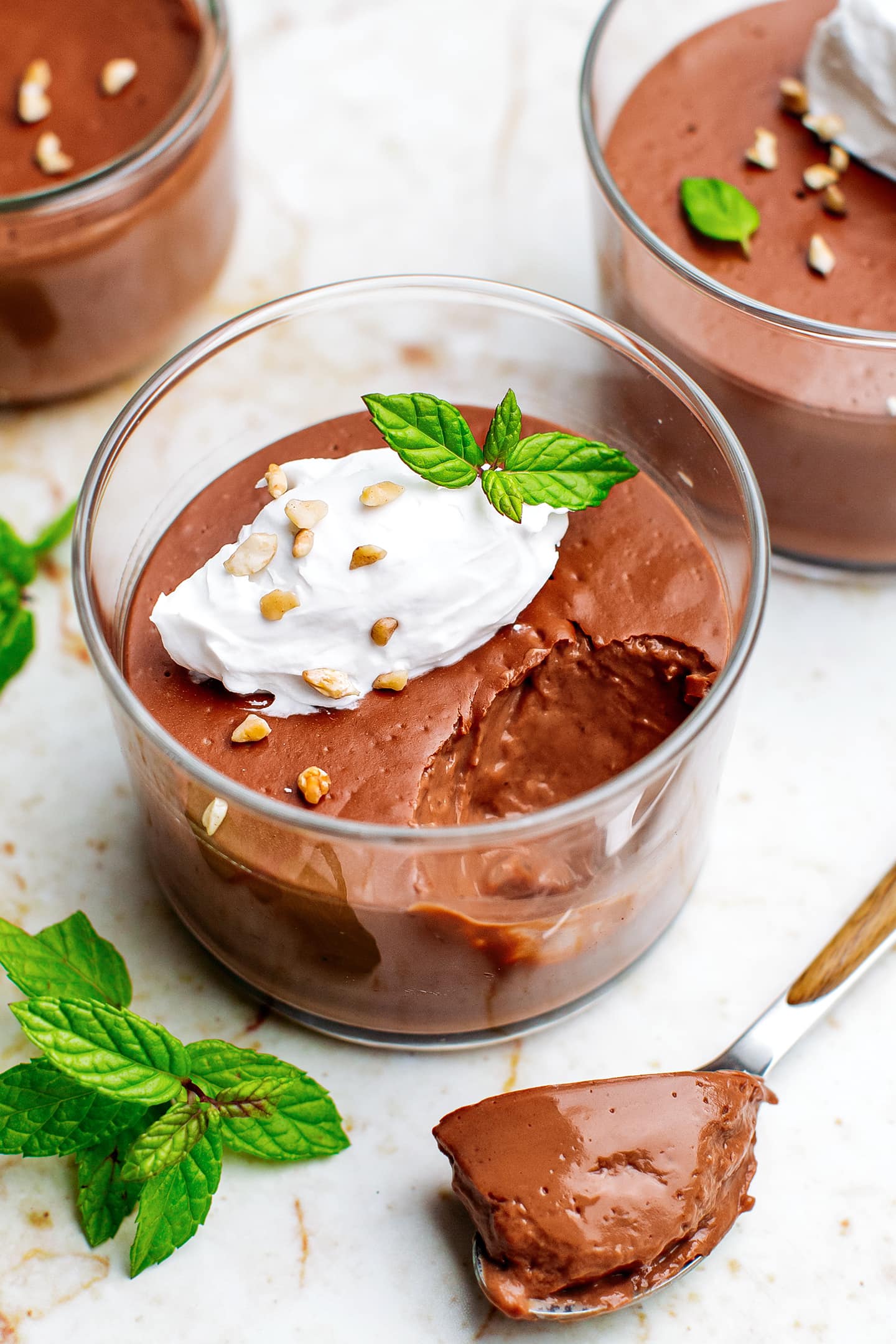 Chocolate pot de crème with coconut cream, crushed nuts, and mint leaves.