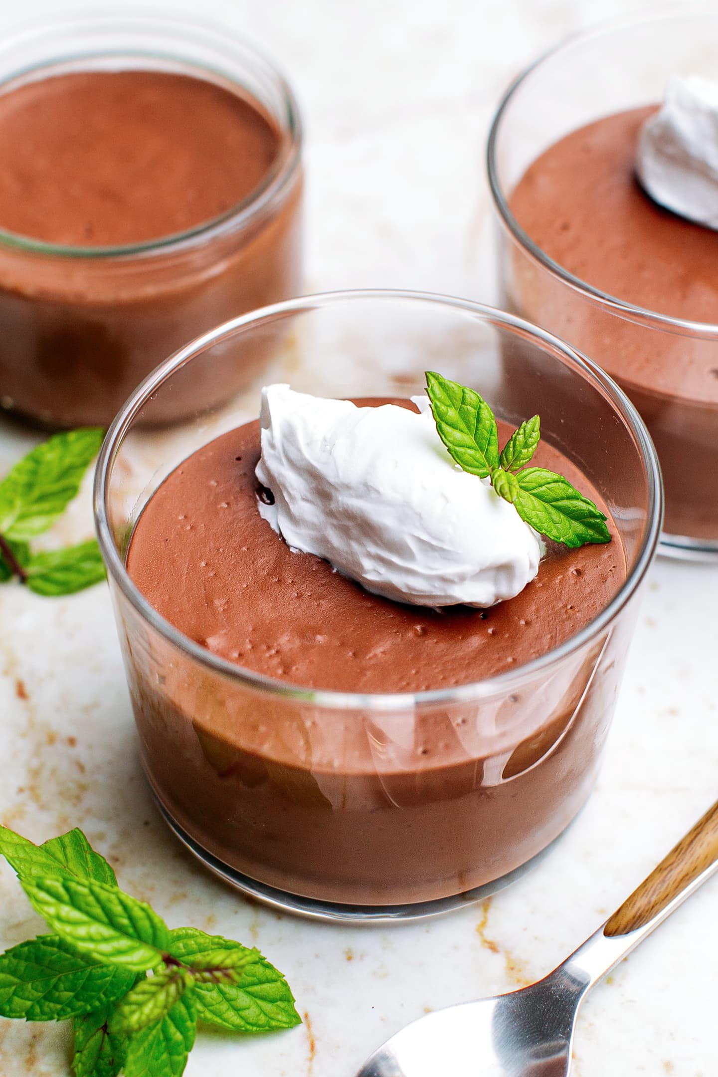 Chocolate pots de crème topped with coconut cream and mint.
