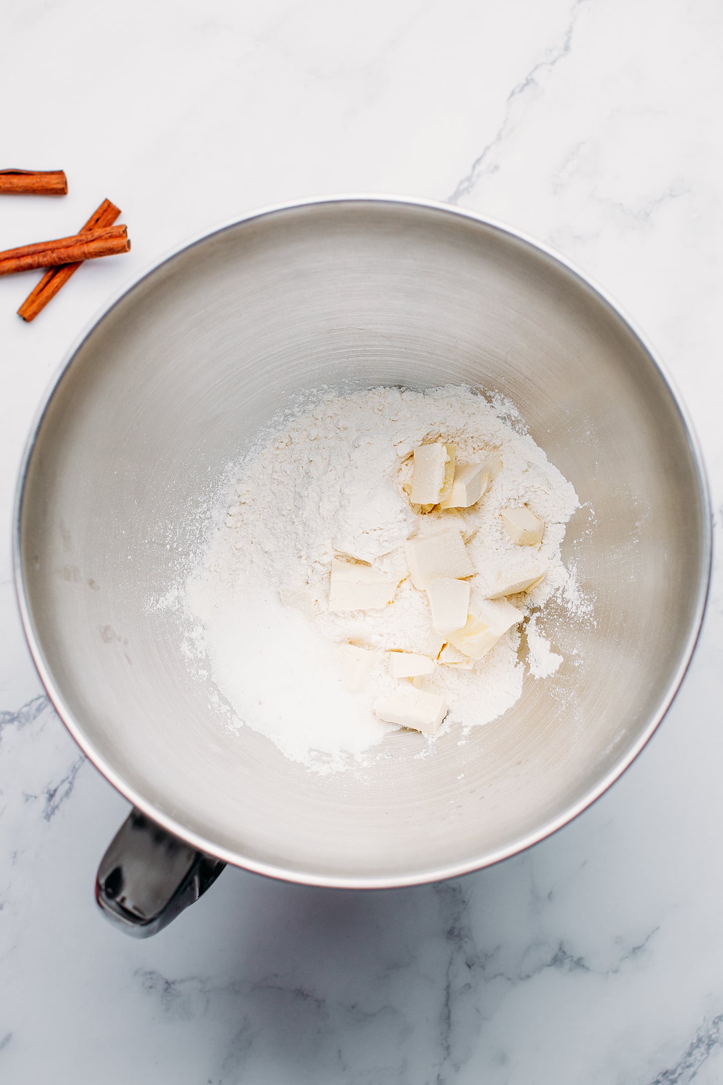 Flour, sugar, and butter in a stand mixer bowl.
