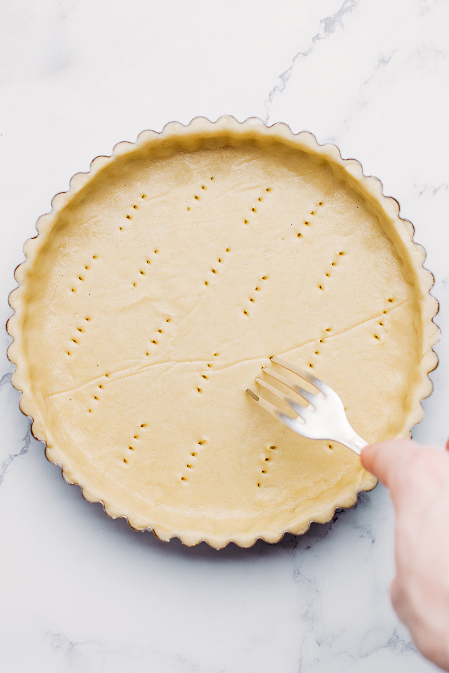 Pricking unbaked pie crust with a fork.