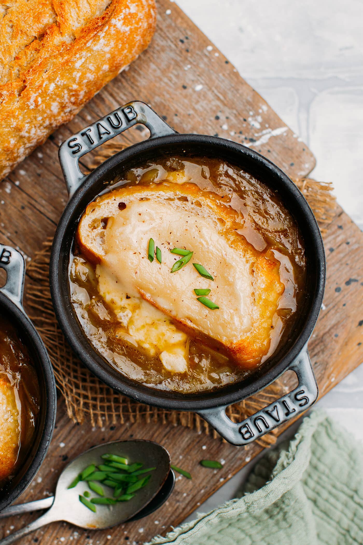 Close up of vegan french onion soup with bread and scallions.