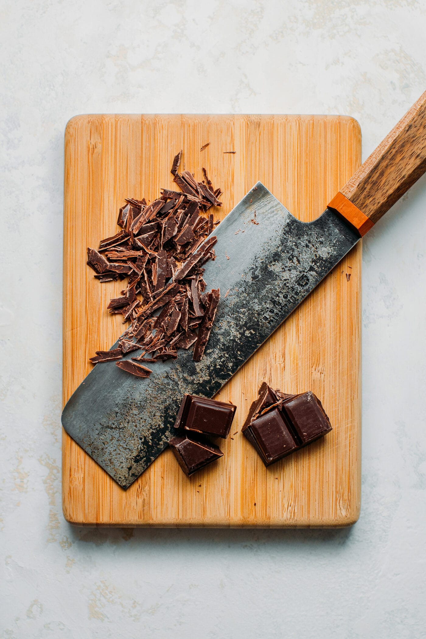 Chopped dark chocolate on a cutting board.
