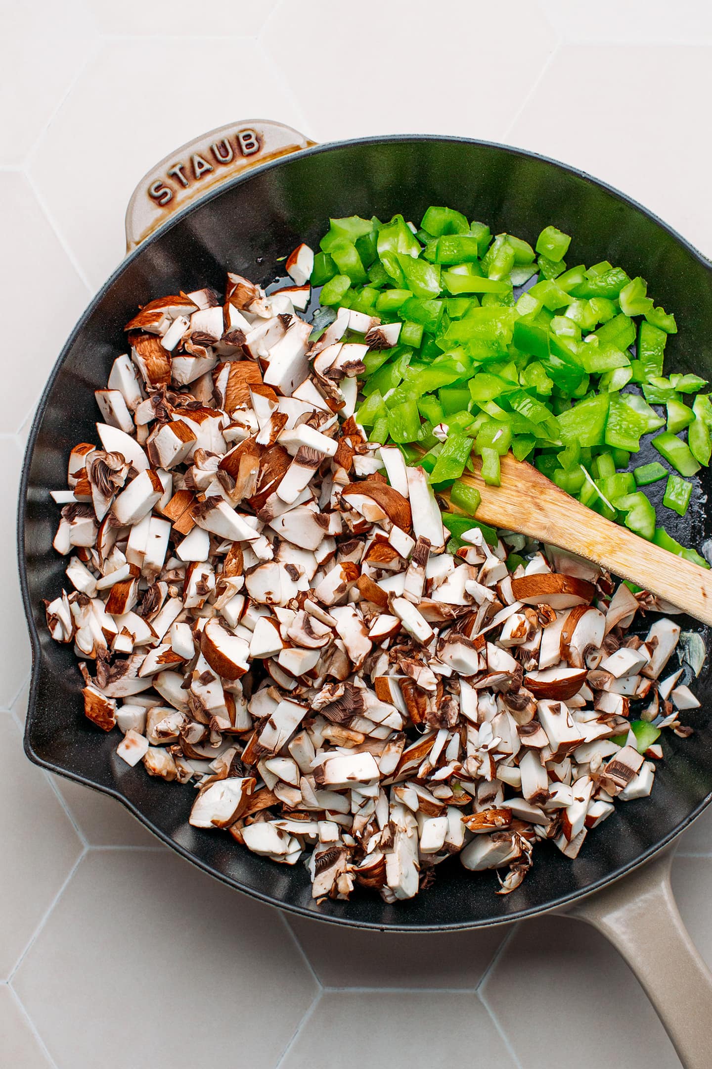 Mushrooms and green bell peppers in a skillet.