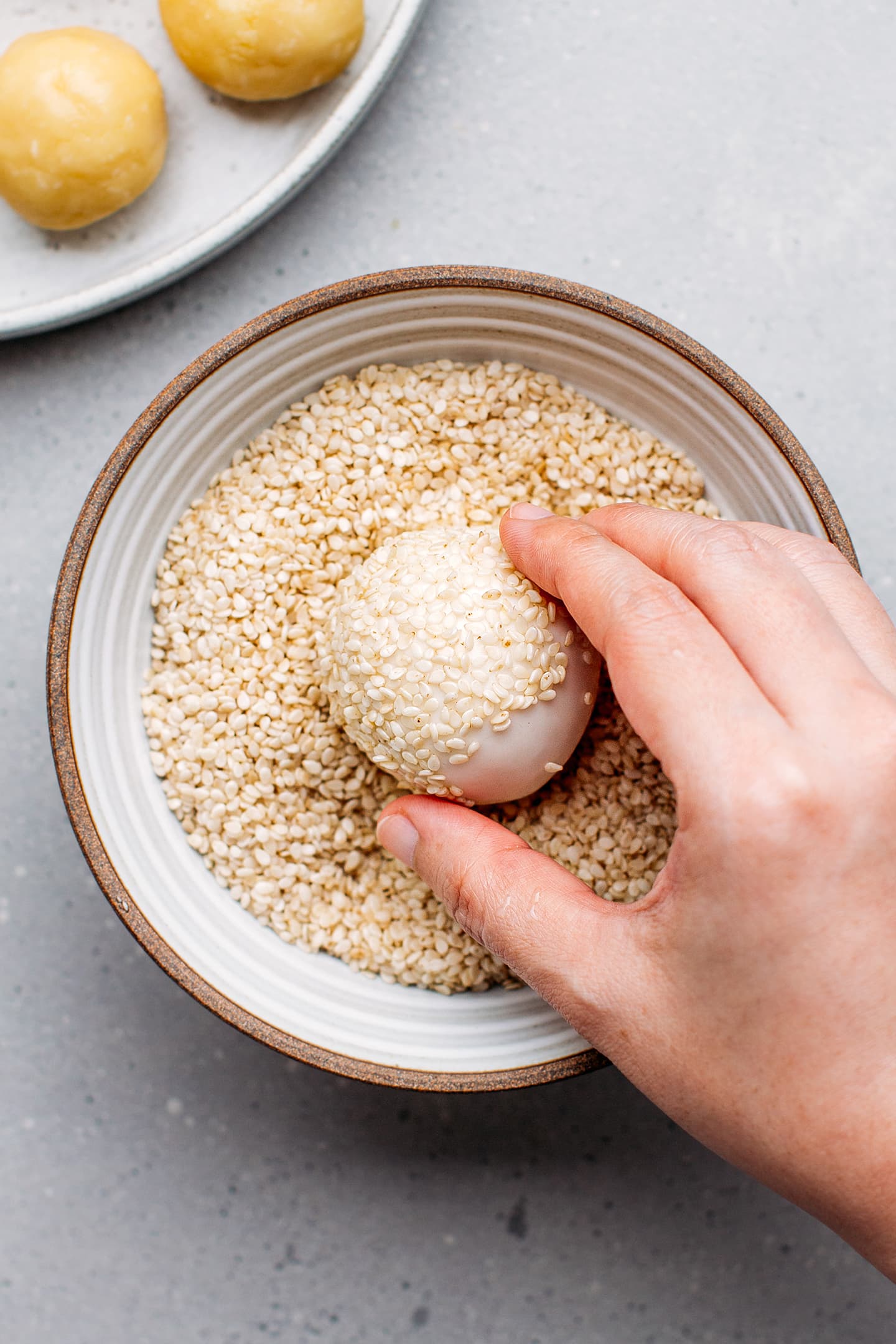 Dipping sweet rice ball into sesame seeds.